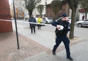 policjant rozwija taśmę z napisem policja