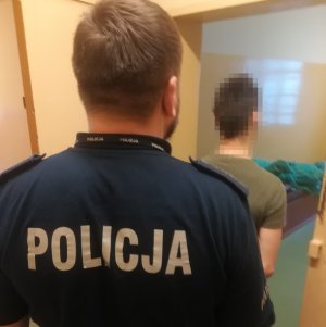 policjant wprowadza zatrzymanego