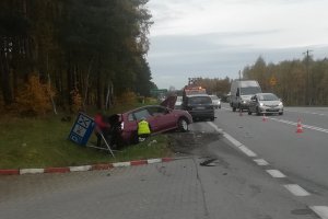 w rowie po lewej stronie drogi k6 znajduje się uszkodzone osobowe bordowe suzuki oraz przewrócona tablica drogowa. Przy suzuki znajduje się odwrócony tyłem umundurowany policjant ruchu drogowego. Przy bagażniku suzuki stoją dwie postaci. Ich sylwetki są niewyraźne. Na lewym poboczu drogi, przed suzuki stoi ciemnoszary ford s-max. Ulicą poruszają się pojazdy