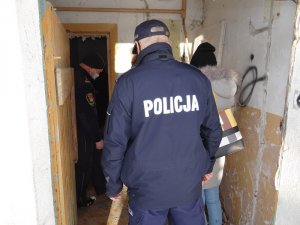 pustostan. W środku znajdują się policjant, funkcjonariusz straży miejskiej i dwoje pracowników socjalnych