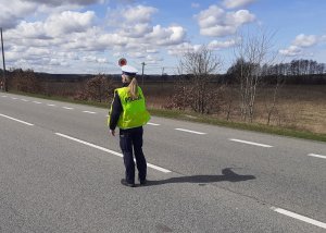 na jezdni stoi policjantka ruchu drogowego z uniesioną do góry tarczą do zatrzymywania pojazdów