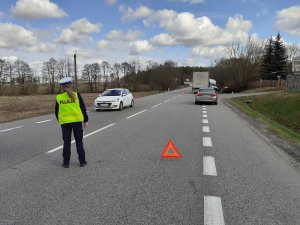 miejsce wypadku drogowego. Policjantka kieruje ruchem. Przed nią, w rowie znajduje się pojazd typu bus, obok niego na poboczu stoi pojazd ciężarowy.