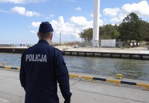 policjant w umundurowaniu ćwiczebnym patroluje teren kanału portowego w Łebie