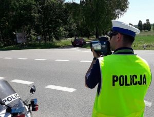 policjant przy drodze mierzy prędkość