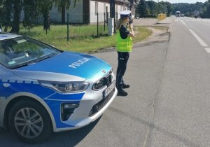 policjant mierzy prędkość przy drodze