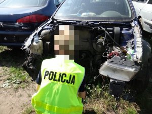 POLICJANCI W KAMIZELKACH ODBLASKOWYCH SPRAWDZAJĄ DEMONTOWANE POJAZDY