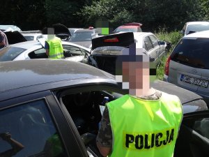 POLICJANCI W KAMIZELKACH ODBLASKOWYCH SPRAWDZAJĄ DEMONTOWANE POJAZDY
