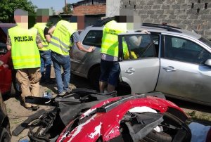 POLICJANCI W KAMIZELKACH ODBLASKOWYCH SPRAWDZAJĄ DEMONTOWANE POJAZDY