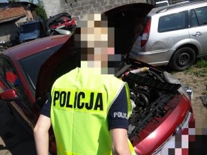 POLICJANCI W KAMIZELKACH ODBLASKOWYCH SPRAWDZAJĄ DEMONTOWANE POJAZDY