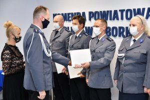 w auli lęborskiej komendy policji komendant wręcza akty mianowania ustawionym w szeregu policjantom