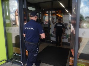 dwaj umundurowani policjanci wchodzą do sklepu