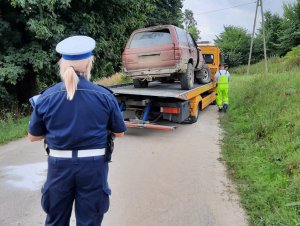 na lawecie znajduje się uszkodzona toyota. Przed lawetą stoi policjantka ruchu drogowego