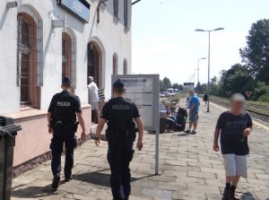 dwaj umundurowani policjanci kierują się w stronę wejścia do budynku dworca PKP w Łebie