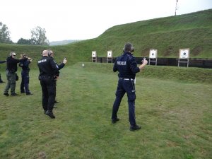 instruktorzy dokonują przeglądu broni po oddaniu strzałów przez szkolonych policjantów