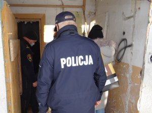 policjant, strażnik miejski i pracownik socjalny sprawdzają wnętrze opuszczonego budynku