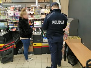 w sklepie umundurowany policjant legitymuje kobietę