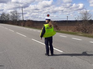 na drodze policjantka ruchu drogowego nadaje sygnał tarczą do zatrzymywania pojazdów