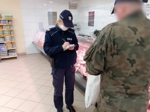 w sklepie przy dziale mięsnym umundurowana policjantka z maseczką ochronną na twarzy legitymuje mężczyznę