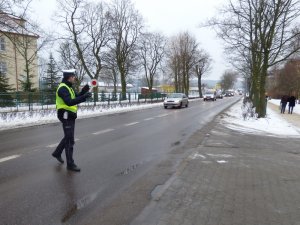 policjant ruchu drogowego nadaje kierowcy samochodu sygnał tarczą do zatrzymywania pojazdów