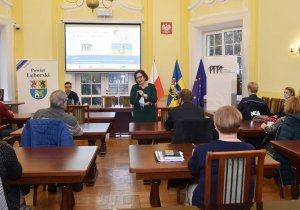 aula lęborskiego starostwa. Przed uczestnikami spotkania stoi Starosta Lęborski, która przemawia do zgromadzonych osób