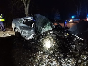 miejsce wypadku, po zmierzchu. Na poboczu drogi, ustawiony prostopadle tyłem do jezdni znajduje się pojazd całkowicie uszkodzonym, wgniecionym przodem. Na jezdni po prawej stronie znajduje się policyjny radiowóz, po lewej stronie policjant w kamizelce odblaskowej