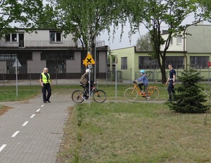 na terenie miasteczka ruchu drogowego lęborskiej komendy Policji policjant i policjantka kontrolują sposób jazdy chłopca i dziewczynki poruszających się rowerami