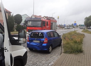 na ulicy stoi uczestnicząca w kolizji granatowa honda jazz z rozbitą tylną szybą. Przed nią znajduje się wóz strażacki