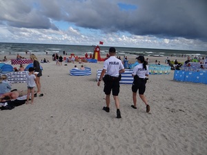 na plaży patrol składający się z policjanta i policjantki idzie w kierunku morza