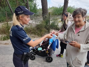 policjantka wręcza ulotkę uśmiechniętej starszej pani