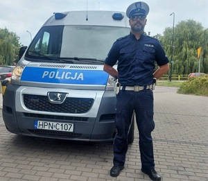 obok radiowozu stoi policjant ruchu drogowego