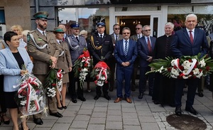 wśród zgromadzonych na placu przed pomnikiem Pocztowców Gdańskich stoi z kwiatami komendant lęborskiej policji