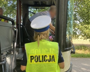 przed wejściem do autokaru stoi policjantka ruchu drogowego. W środku znajduje się kierowca