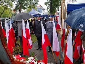 przed pomnikiem Zesłańców Sybiru stoi komendant lęborskiej policji i przedstawiciel straży pożarnej