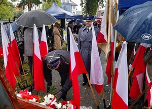 przed pomnikiem Zesłańców Sybiru stoi komendant lęborskiej Policji. Przedstawiciel lęborskiej straży pożarnej składa kwiaty pod pomnikiem