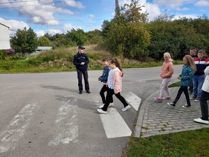 przez przejście przechodzą w parach uczniowie. Na jezdni stoi policjantka