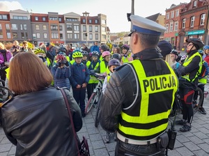 na placu stoją starosta lęborski, policjant ruchu drogowego i policjantka prewencji którzy rozmawiają ze zgromadzonymi uczestnikami rajdu