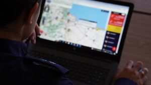 przed ekranem laptopa siedzi policjantka. Na ekranie wyświetla się krajowa mapa zagrożeń bezpieczeństwa