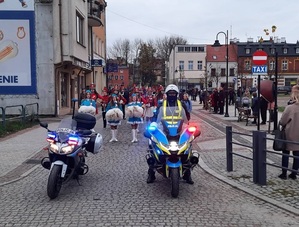 na czele przemarszu ulicami miasta znajduje się policjant na motocyklu