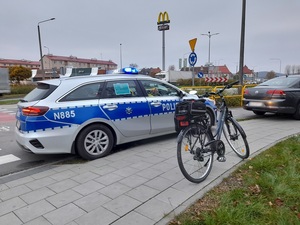 na chodniku obok policyjnego radiowozu stoi rower. Przed radiowozem znajduje się grafitowy vw passat