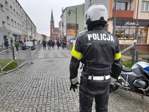 policjant ruchu drogowego w ubiorze motocyklisty patrzy na dzieci zgromadzone na linii startu