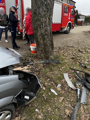 przy drzewie obok wozu straży pożarnej oraz rozbitego samochodu stoi policjantka, która legitymuje kobietę