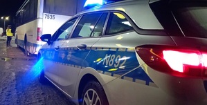 POLICJANT STOI PRZY AUTOBUSIE I OBOK RADIOWOZU
