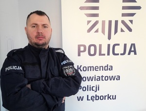 policjant w umundurowaniu służbowym stojący przy roll up z napisem Komenda Powiatowa Policji w Lęborku