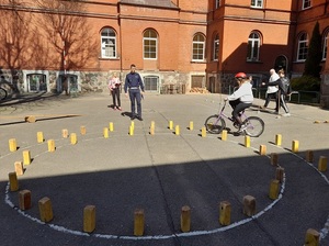 na placu szkolnym policjant ruchu drogowego nadzoruje przejazd rowerzystki po torze przeszkód