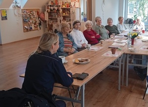 w sali budynku PCPR policjantka rozmawia z siedzącymi przy stole seniorami