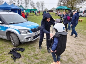 na festynie przy oznakowanym radiowozie policjantka nakłada dziewczynce policyjny sprzęt ochronny