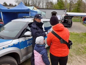 na festynie policjantka wręcza kobiecie ulotkę