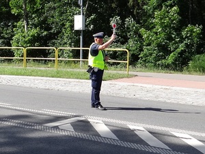 policjant ruchu drogowego trzyma w górze tarczę do zatrzymywania pojazdów