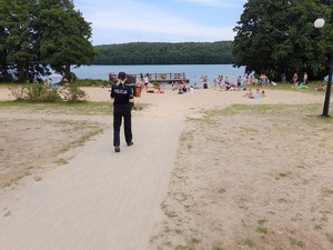 nad jeziorem policjantka idzie w kierunku zaludnionej plaży