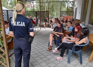 policjantka prowadzi rozmowę z młodzieżą siedzącą na tarasie